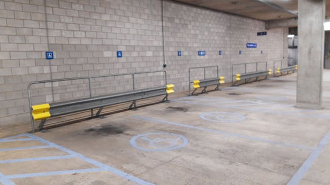 Car park bays with blue accessible parking symbol, with flat level concrete flooring.