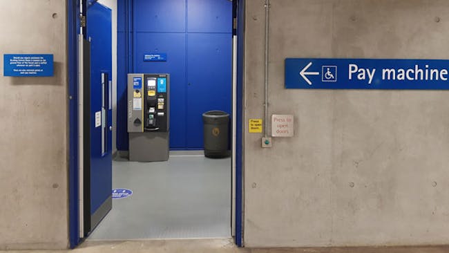 Automatic door with push button to open, level flooring leading to a pay machine.