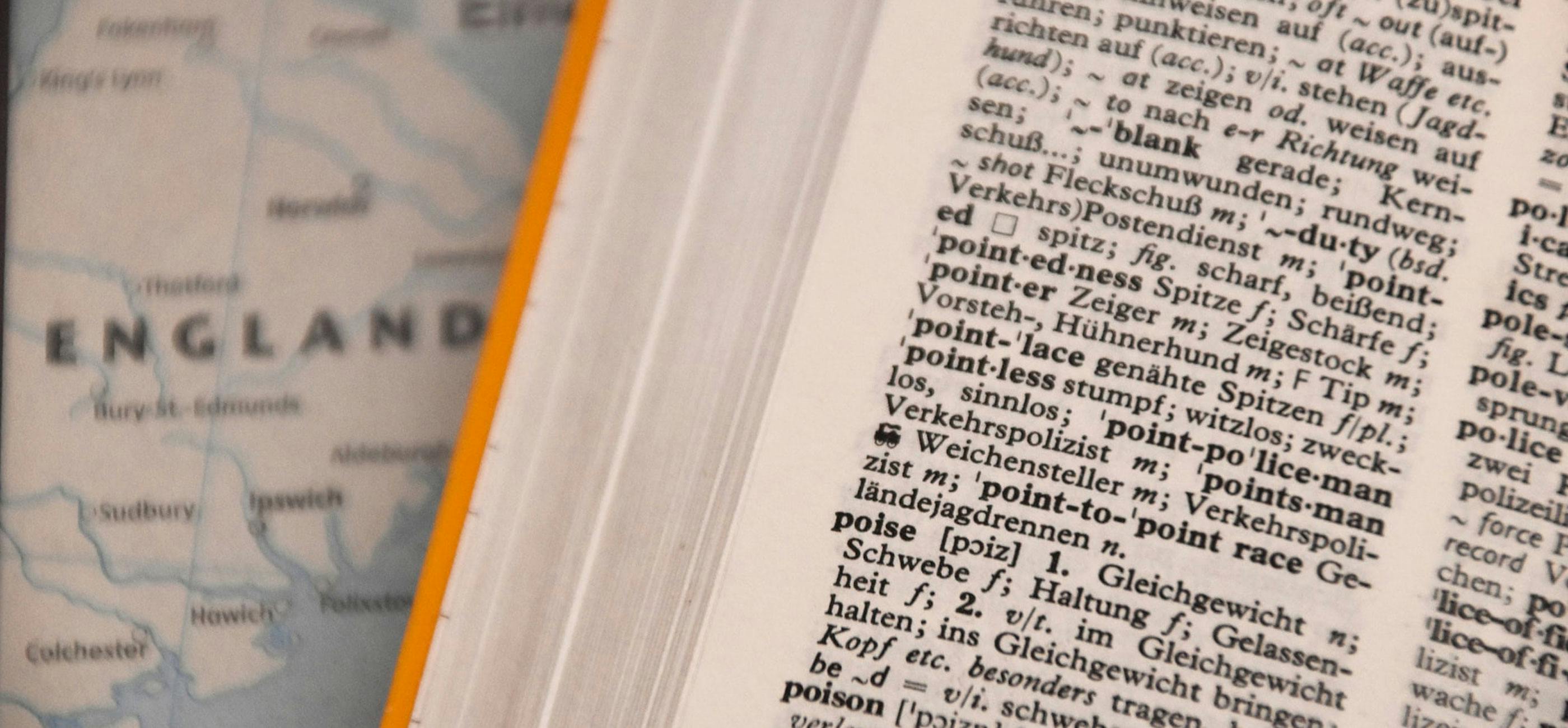 Close up of an English dictionary with a map of the UK in the background.