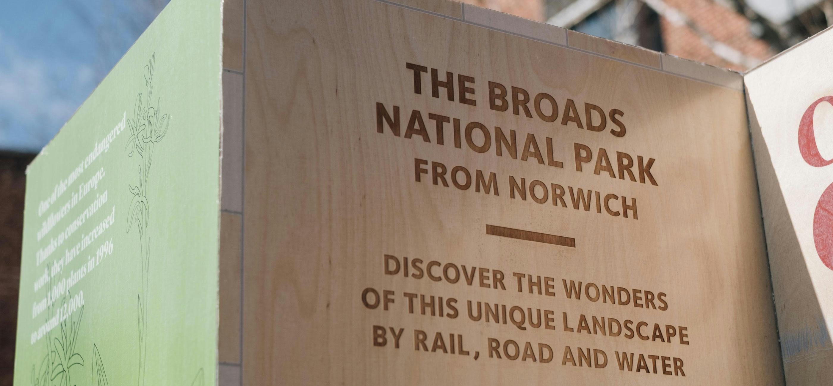 A close up of a wooden pillar with the title The Broads National Park from Norwich.