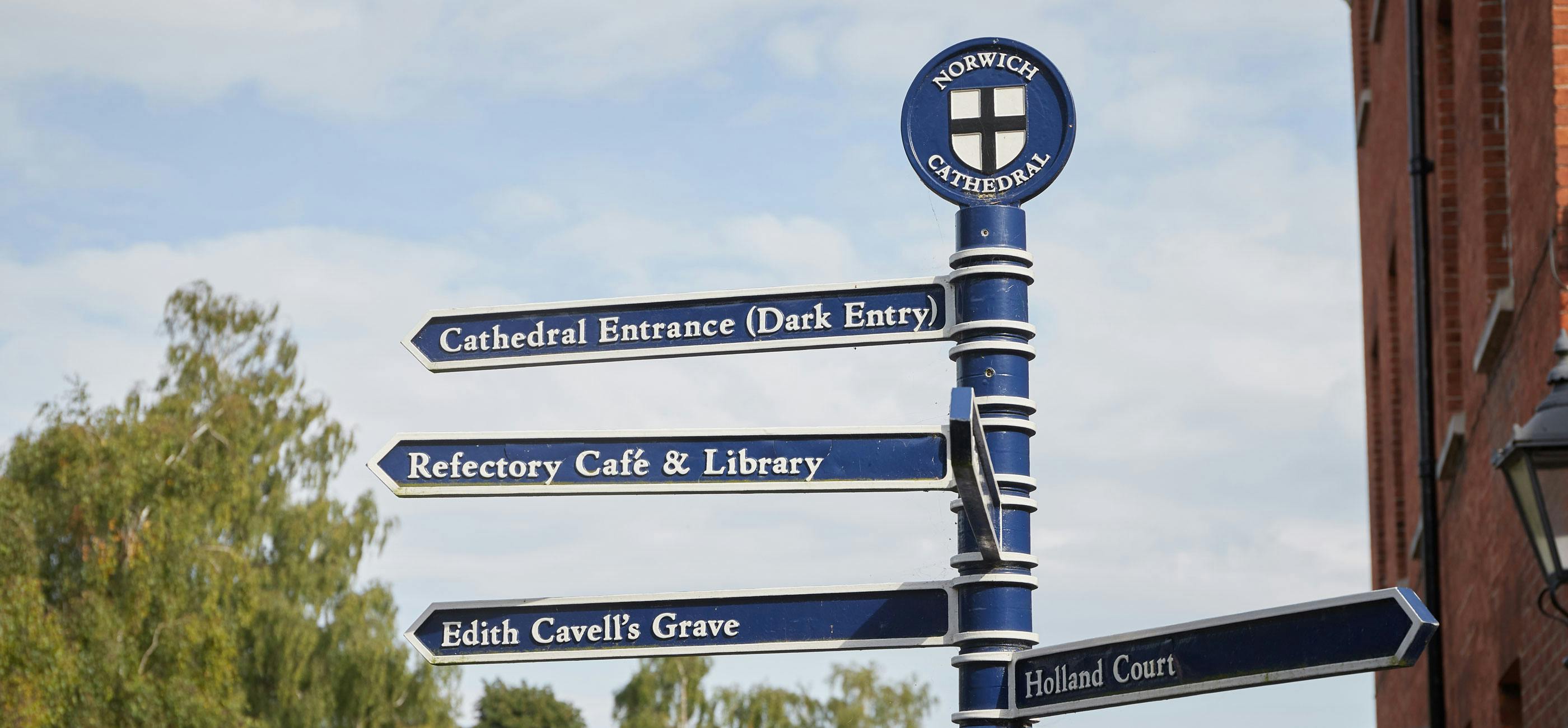 A blue metal directional sign with Norwich tourist destinations.