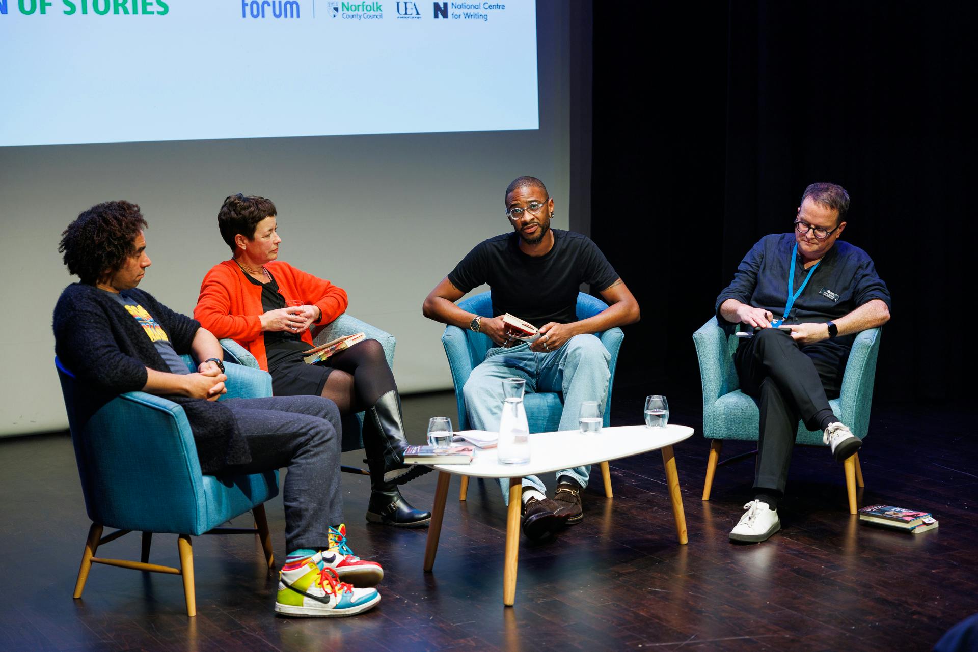 A group of men and women on stage discussing a book