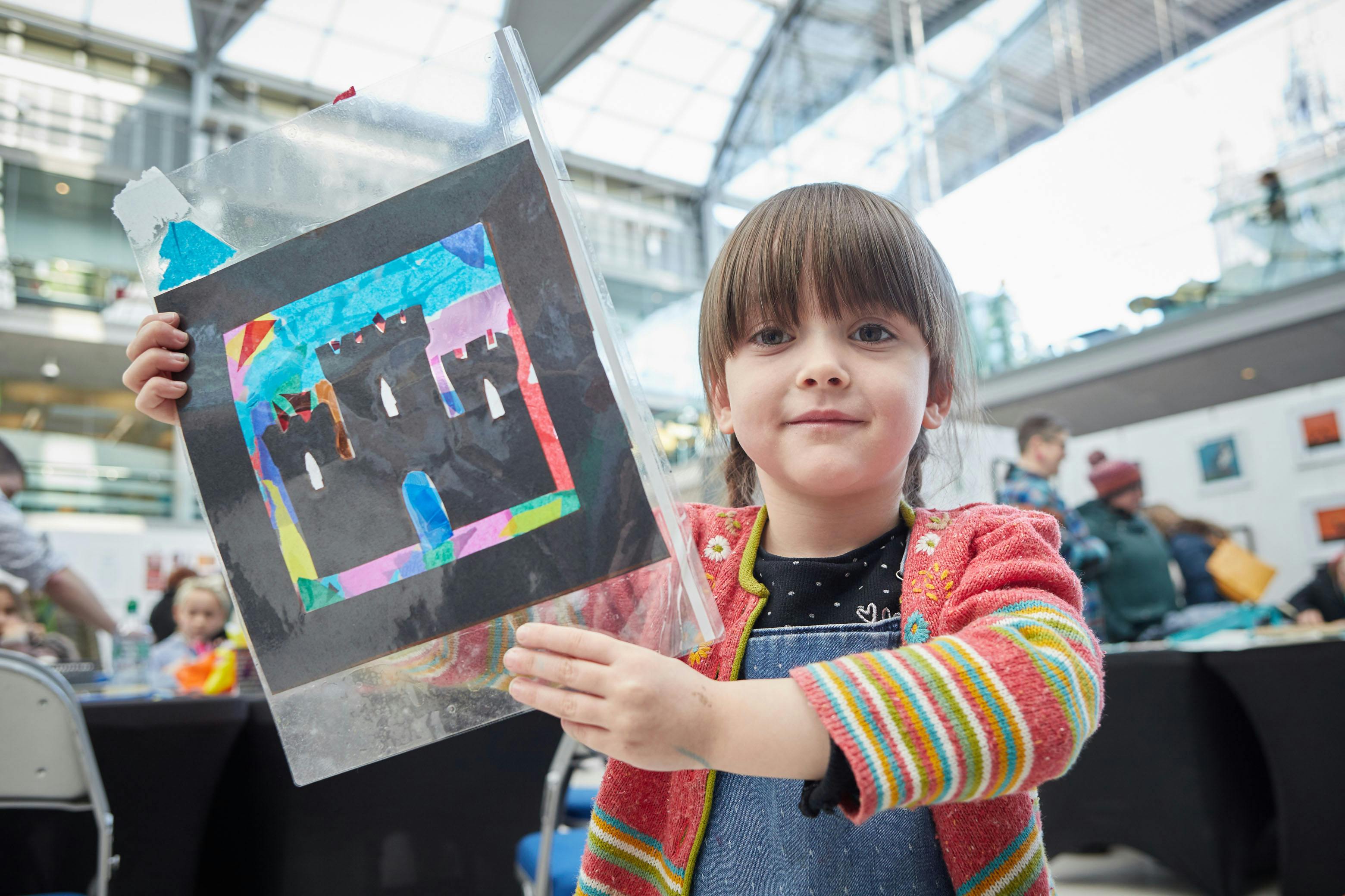 Little girl proudly holding artwork at Norfolk MaKers Festival