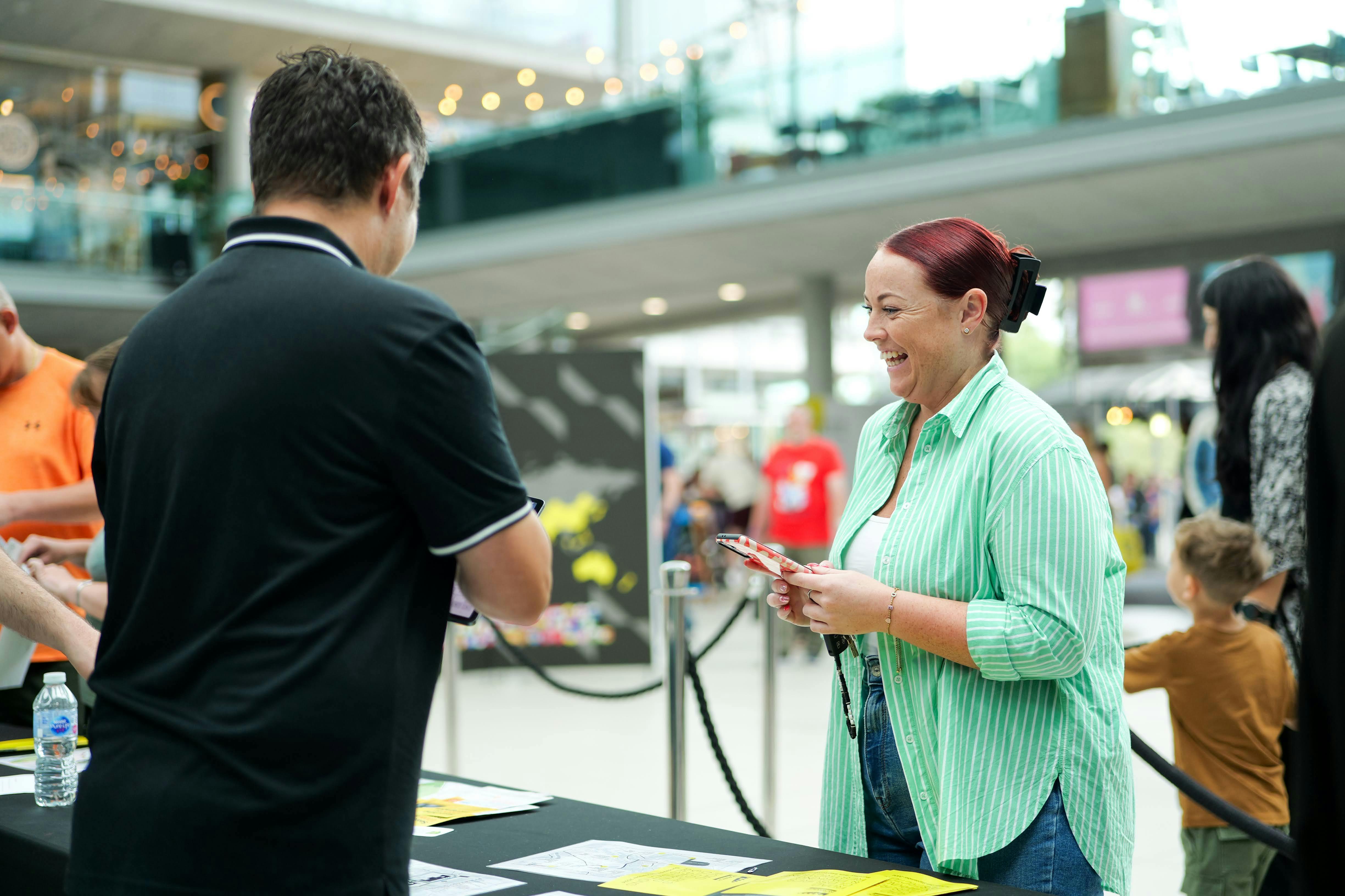 Smiling woman collecting race pack from stand.