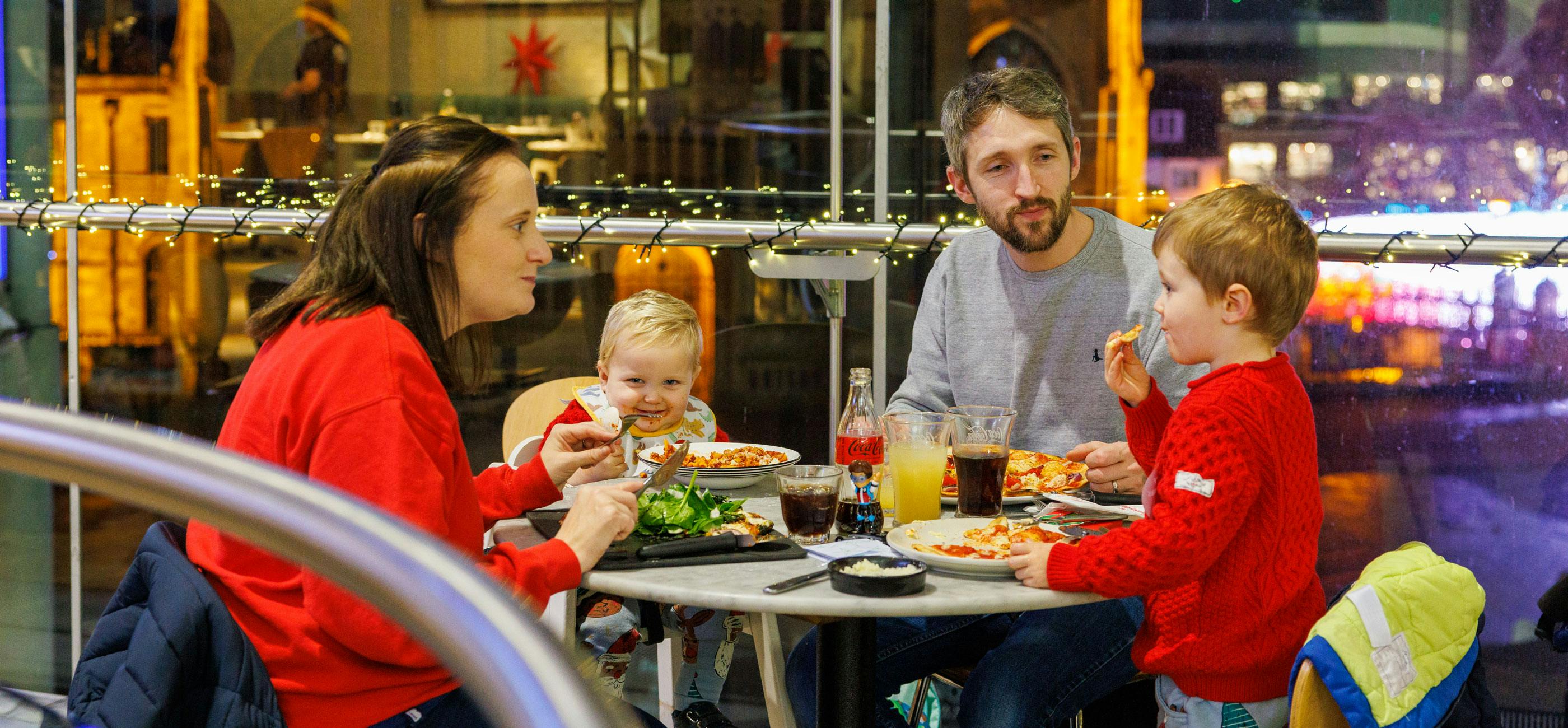A family enjoy a meal at Pizza Express with pizza and pasta.