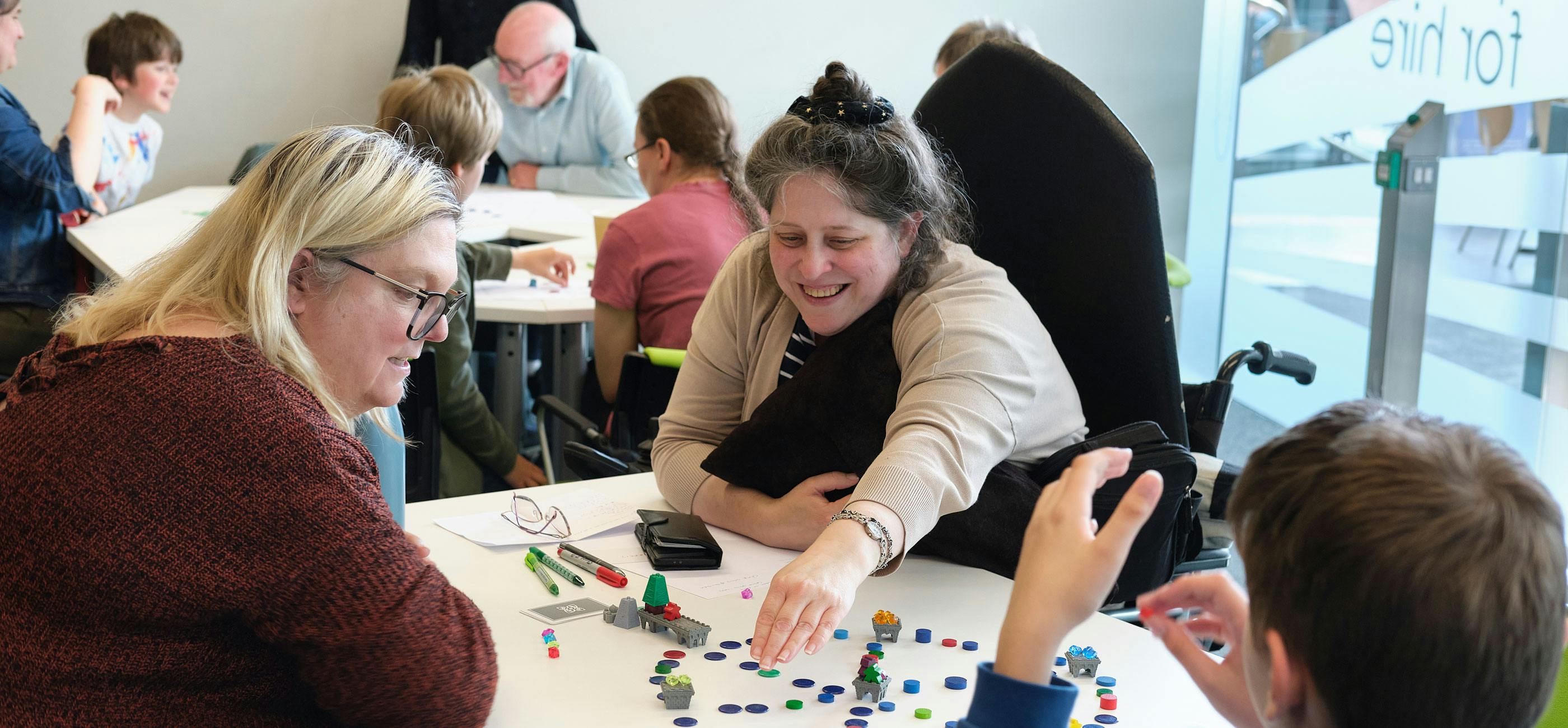 A group of people smile while playing a board game.