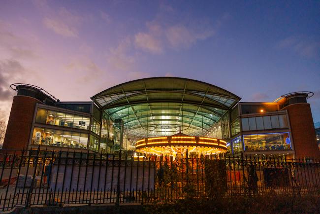The Forum building exterior at sunset with the glow of the traditional Christmas carousel in the foreground.