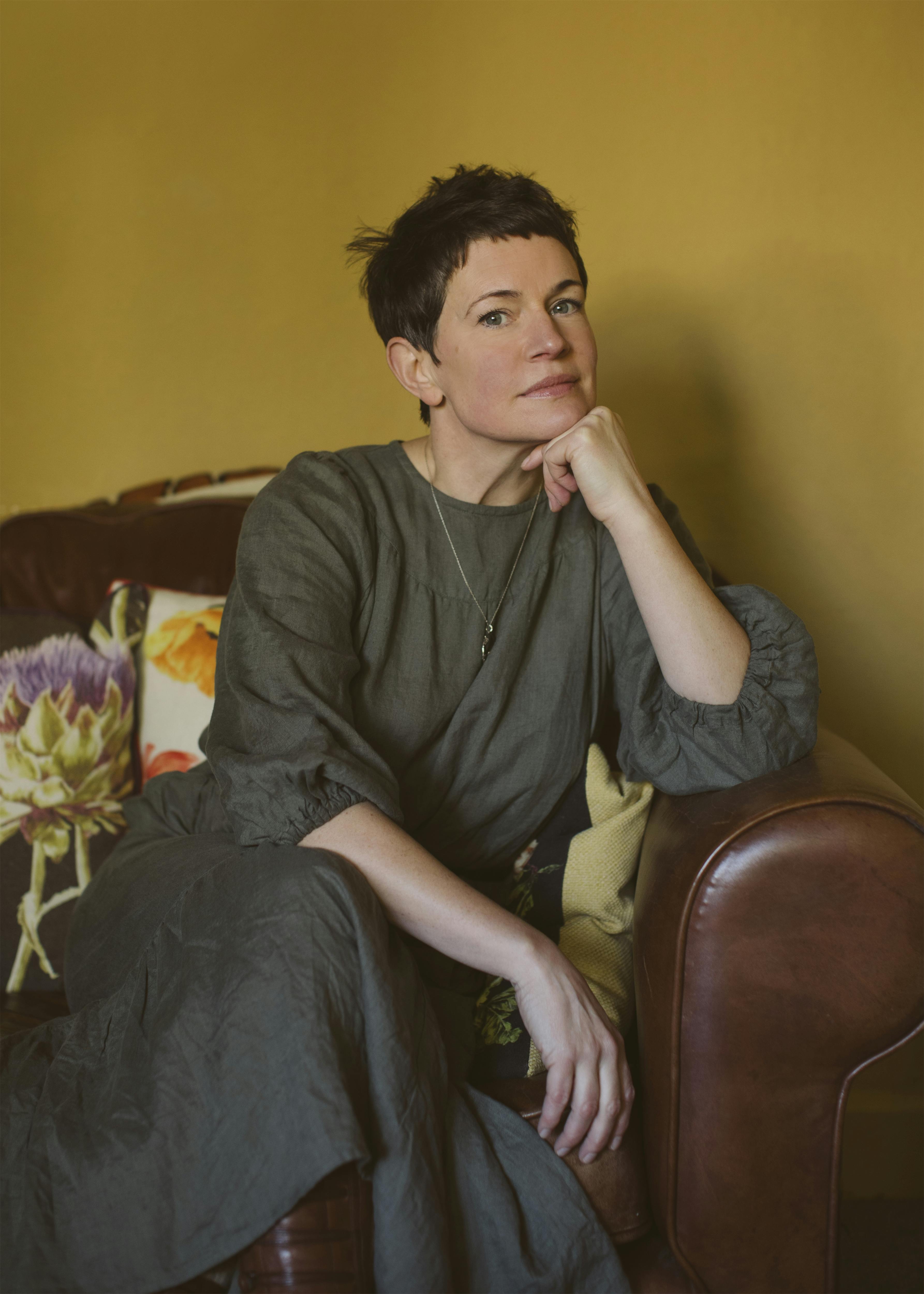 Author Sarah Hall sitting on a brown sofa.