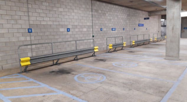 Car park bays with blue accessible parking symbol, with flat level concrete flooring.
