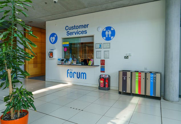 A reception with a glass window and Customer Services sign