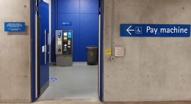 Automatic door with push button to open, level flooring leading to a pay machine.