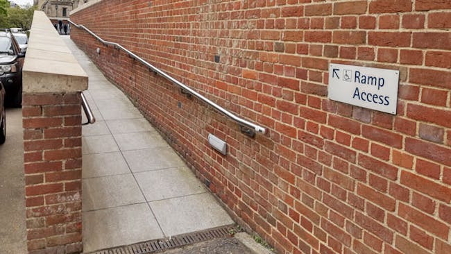 A ramp with two red brick walls and railings either side.