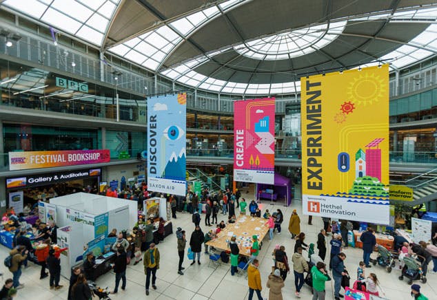 A busy events space with activity tables, lots of people and big banners.