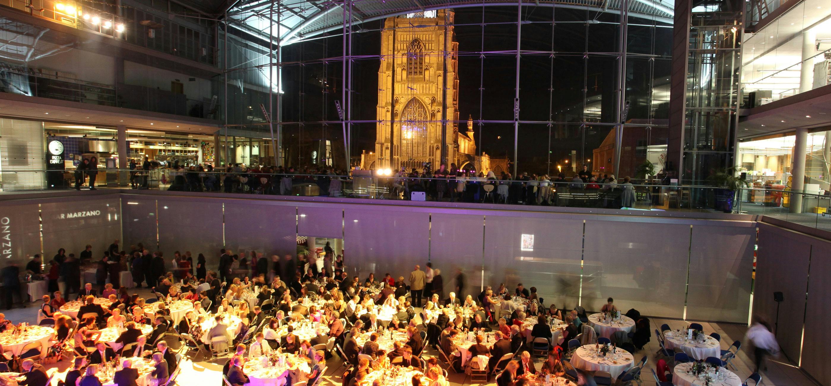 atrium-private-event.jpg A formal event with tables in The Atrium of The Forum in the evening with St Peter Mancroft lit up outside.