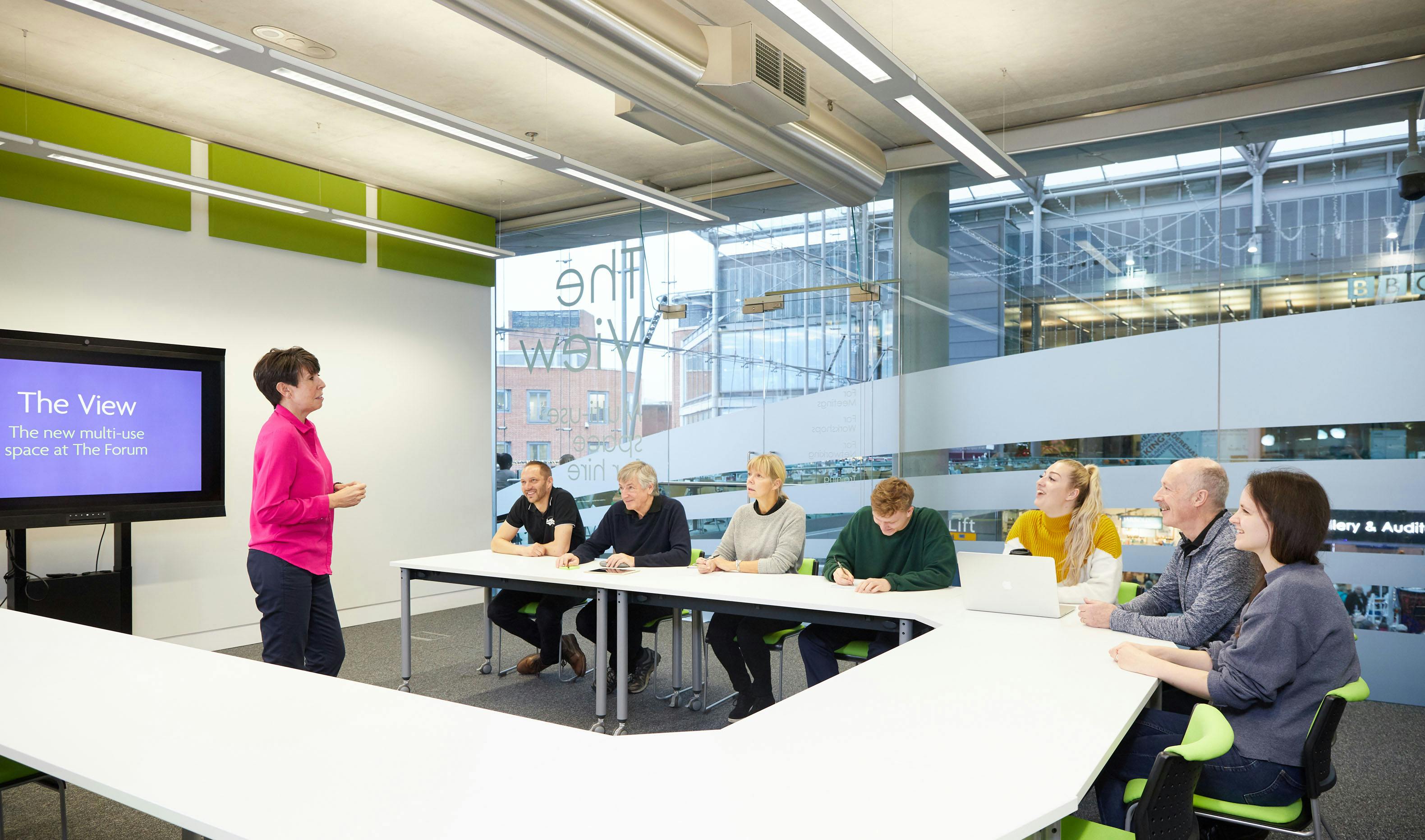 A lady gives a presentation to a group of people.