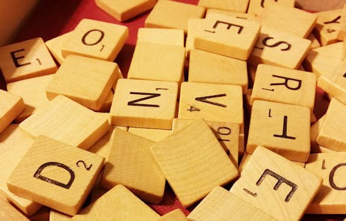Wooden scrabble board game pieces with letters on.