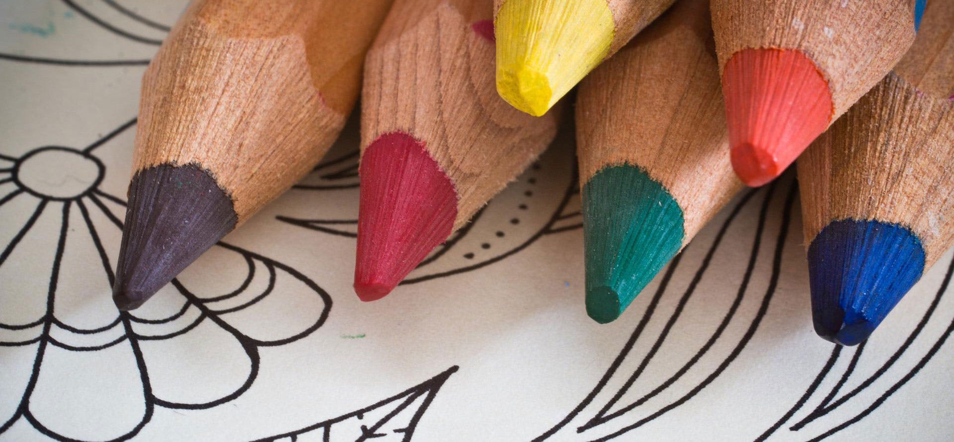 A selection of coloured pencils on top of a colouring book.