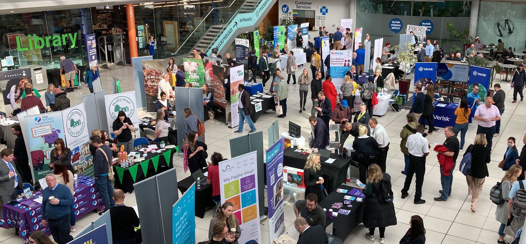 A view looking down on a jobs fair with lots of employer stands and people talking.