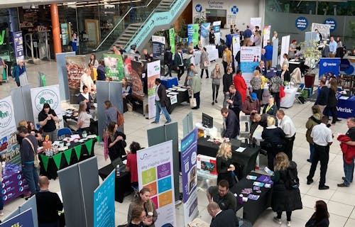 A view looking down on a jobs fair with lots of employer stands and people talking.