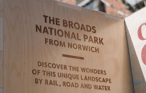 A close up of a wooden pillar with the title The Broads National Park from Norwich.
