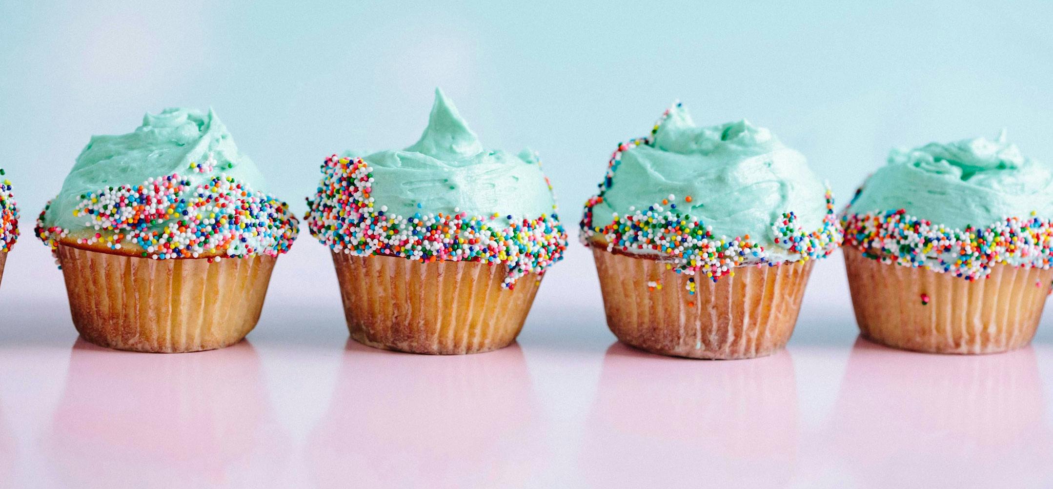 Cupcakes with turquoise icing and rainbow sprinkles.