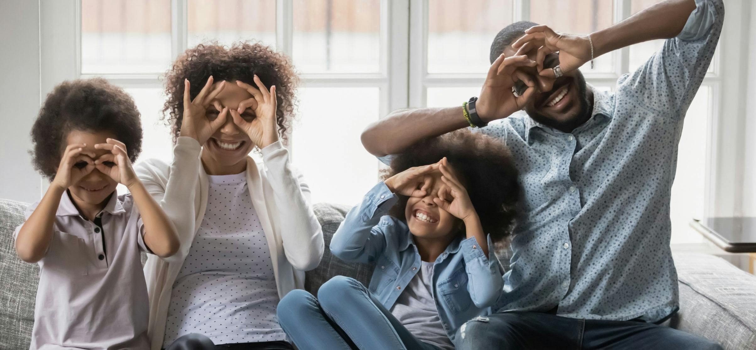A family create binoculars with their hands and smile.