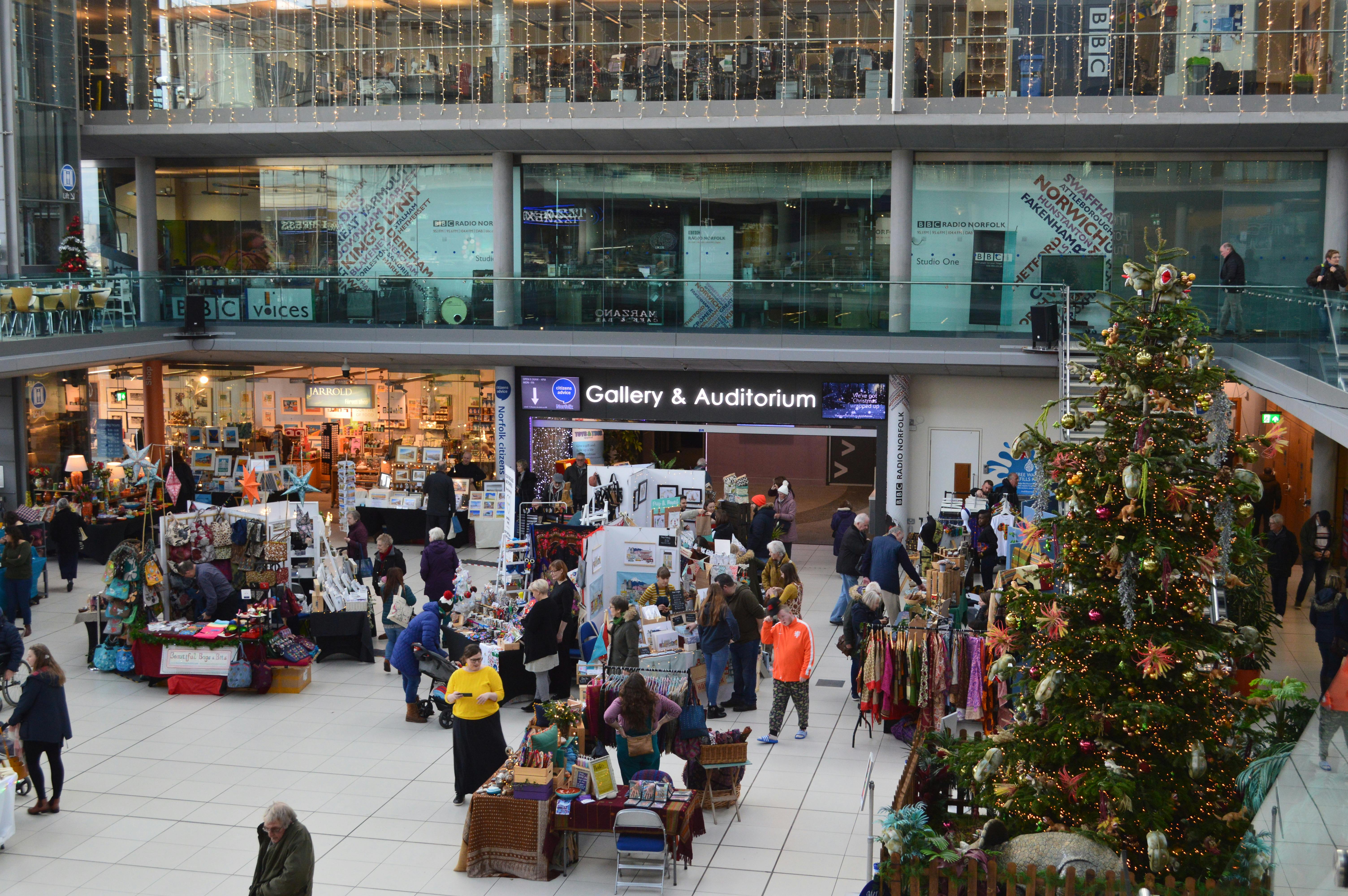 Christmas Tree and Global Village Christmas Marketing in The Forum's Atrium, people browse stalls.