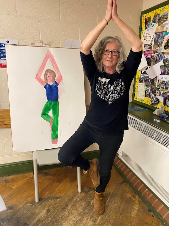 woman in yoga pose in front of painting of woman doing yoga pose