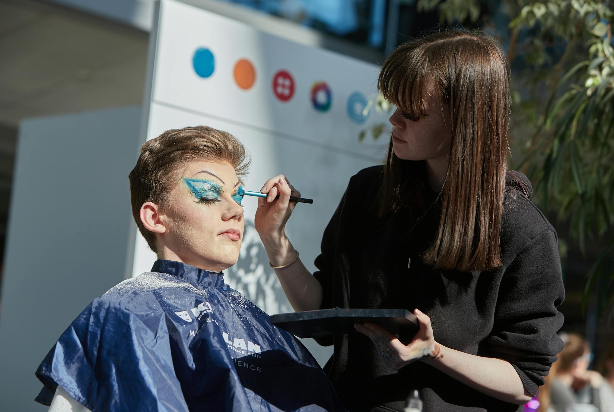 Young person having blue eye make up applied with brush