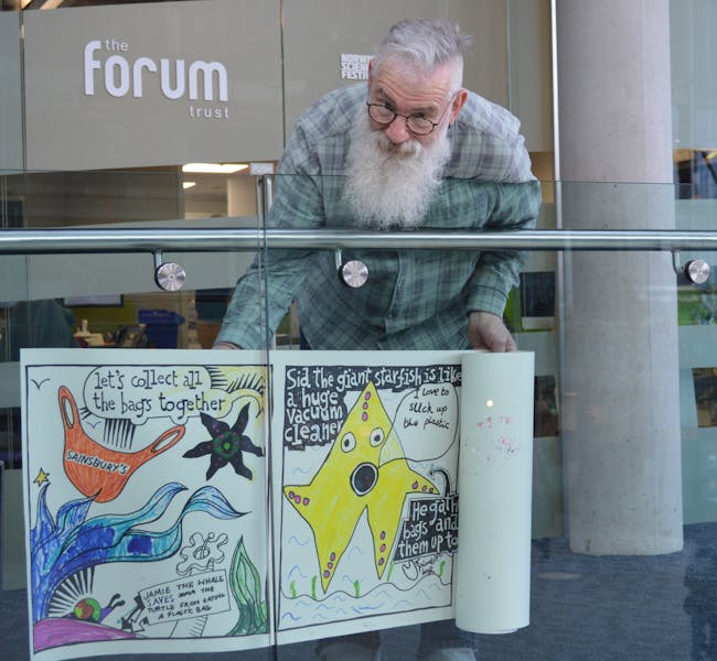 Man holding a large scale cartoon on a roll of paper