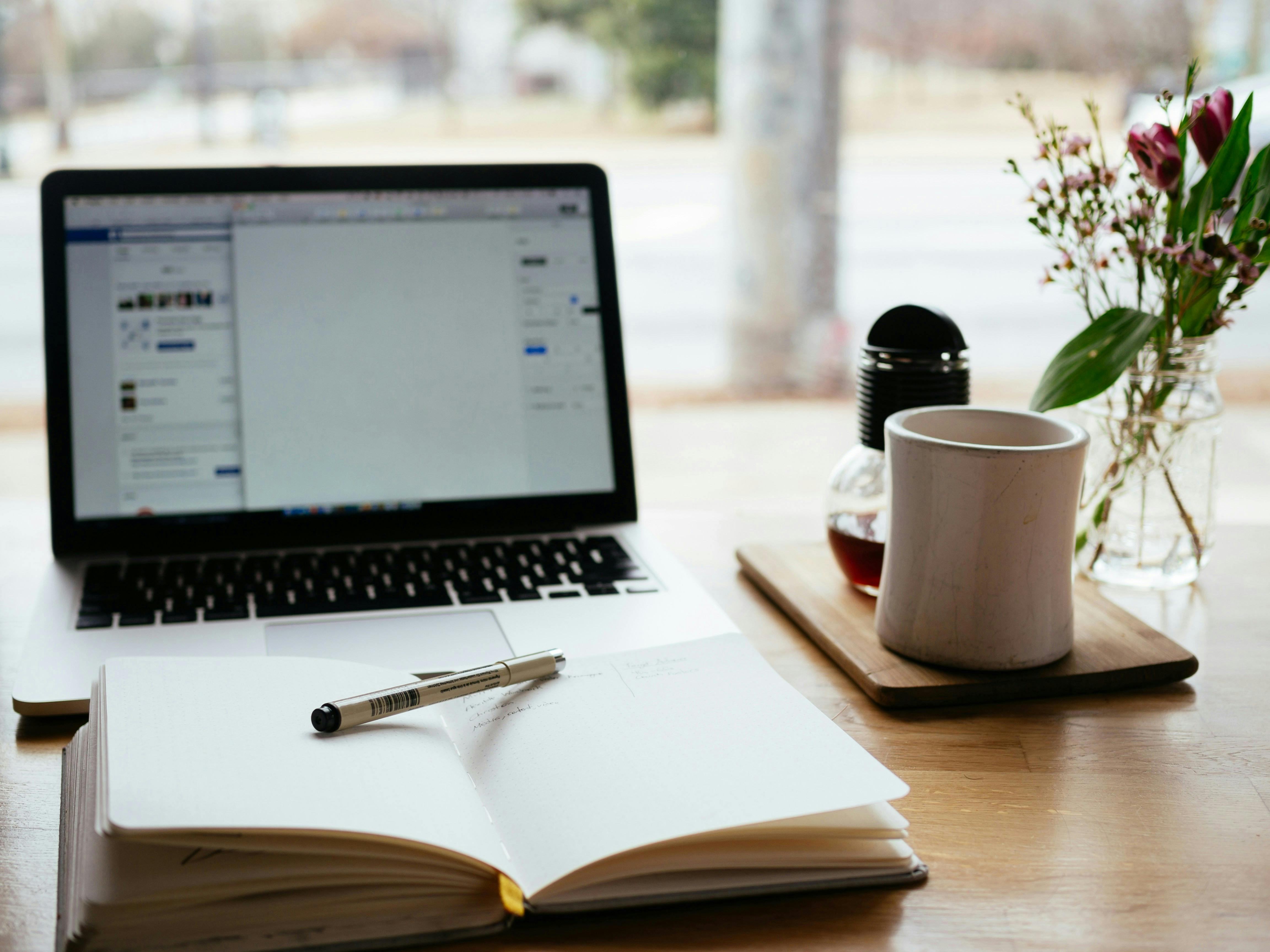 notebook, laptop and coffee cup on a table