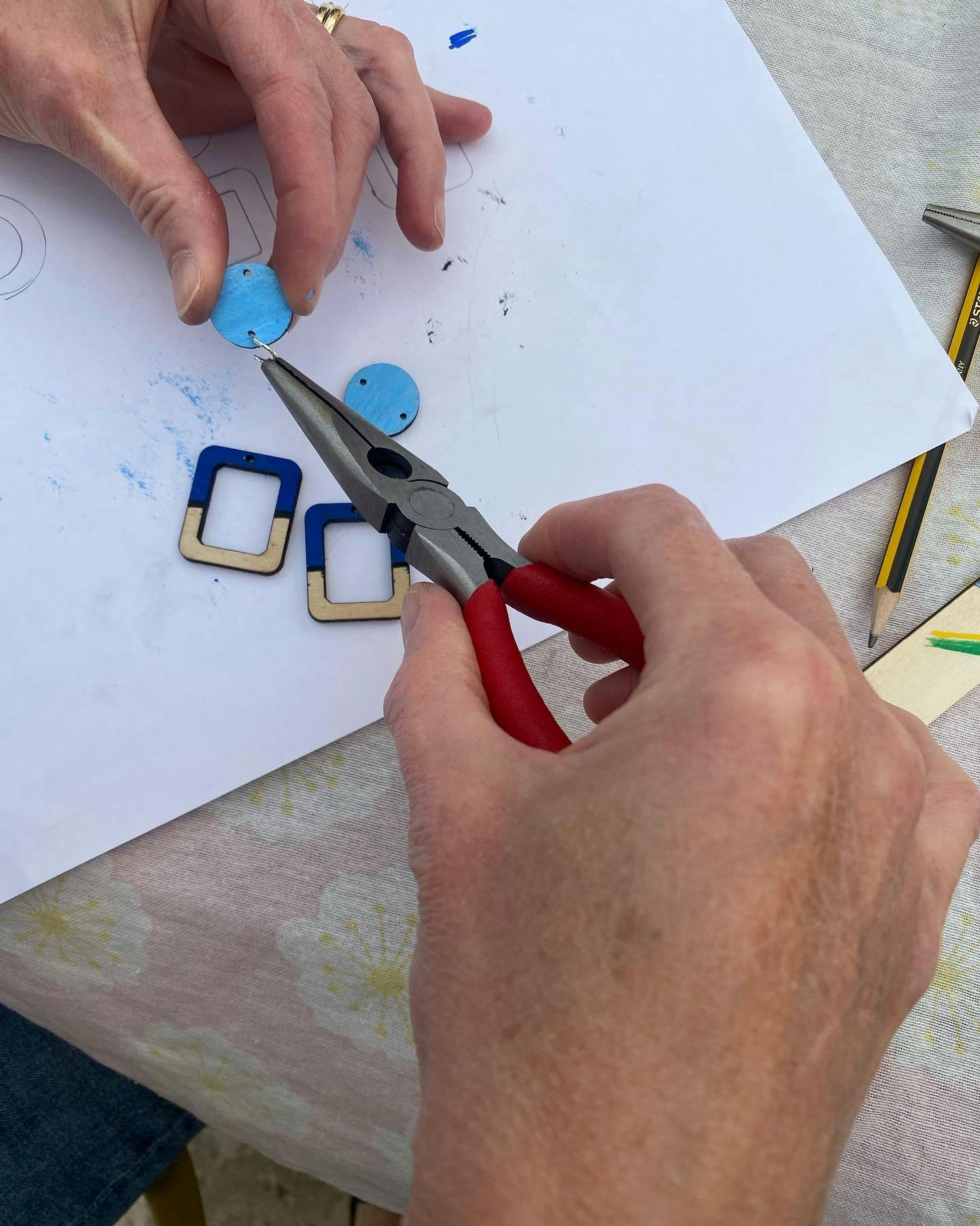 Hands making wooden jewellery.