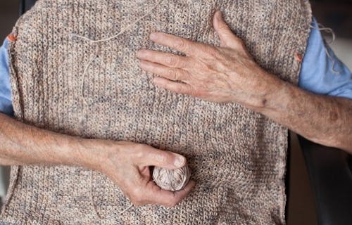 old man'shands holding an unfinished piece of knitting
