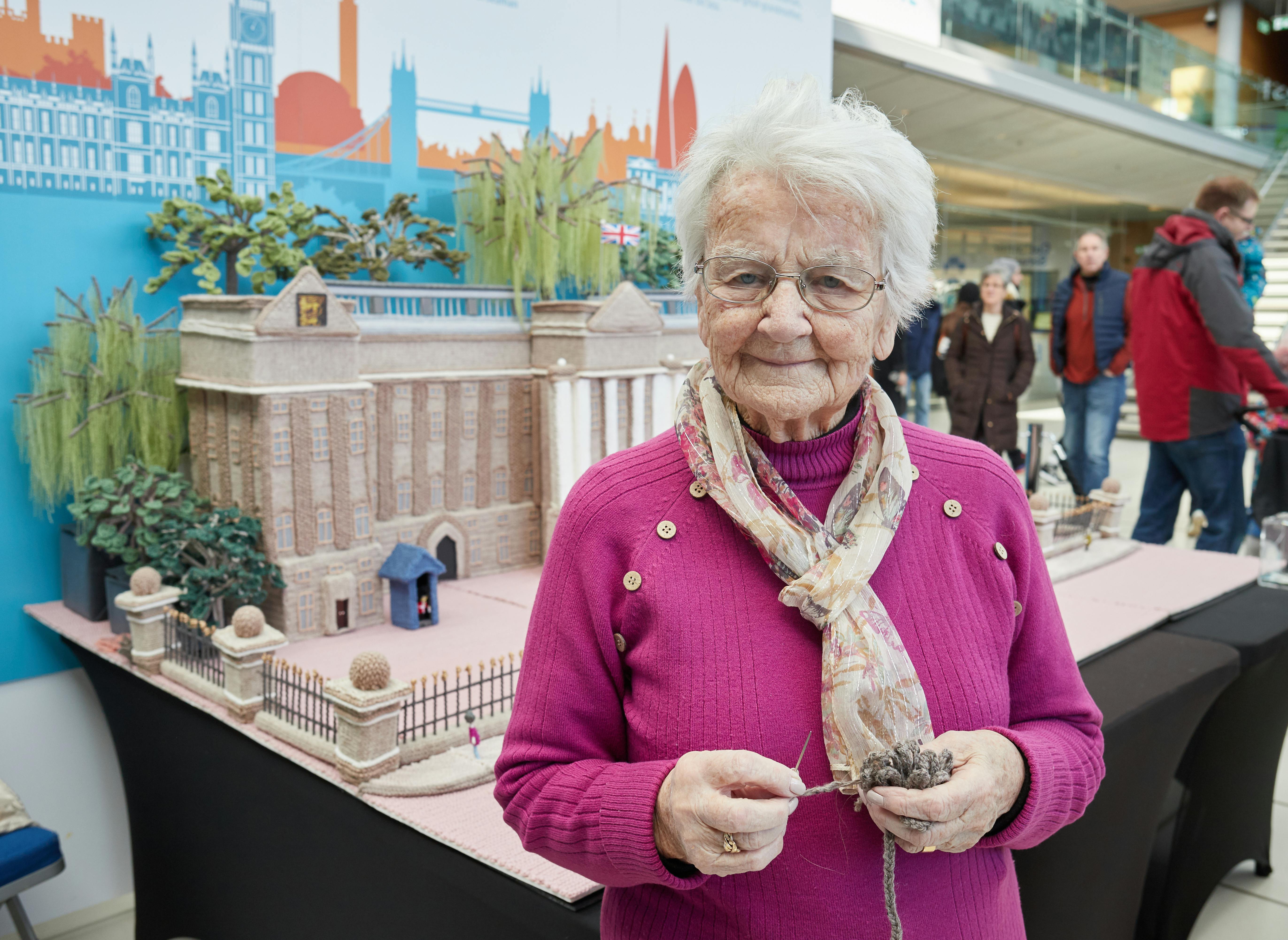 Woman standing in front of knitted Buckingham Palace