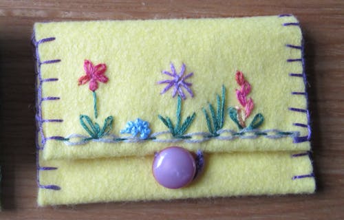 A yellow felt purse with embroidered flowers