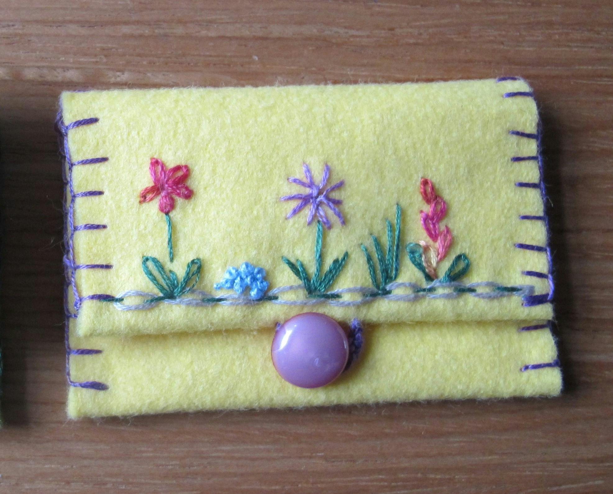 A yellow felt purse with embroidered flowers