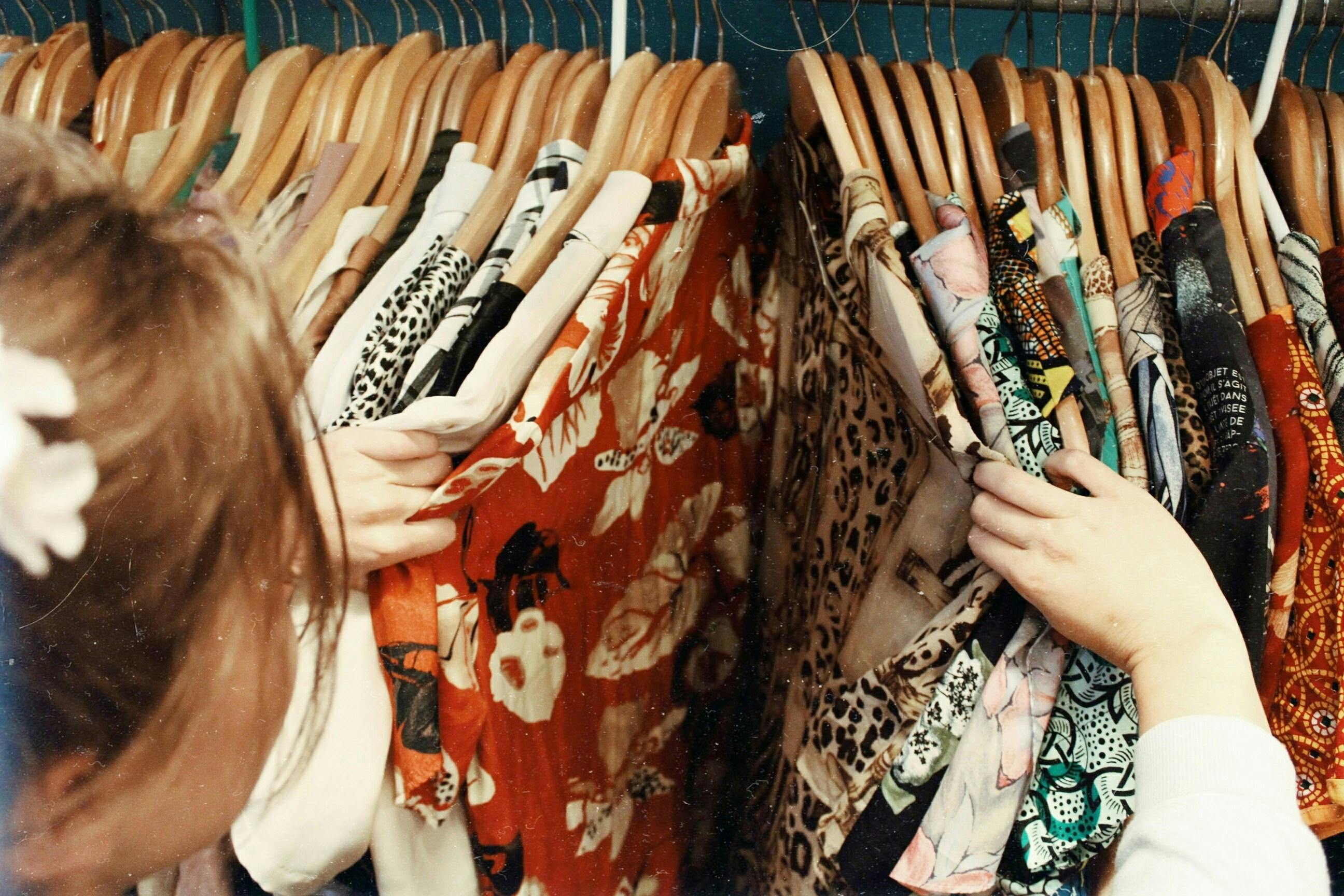 A woman looks through a rail of vintage clothes.