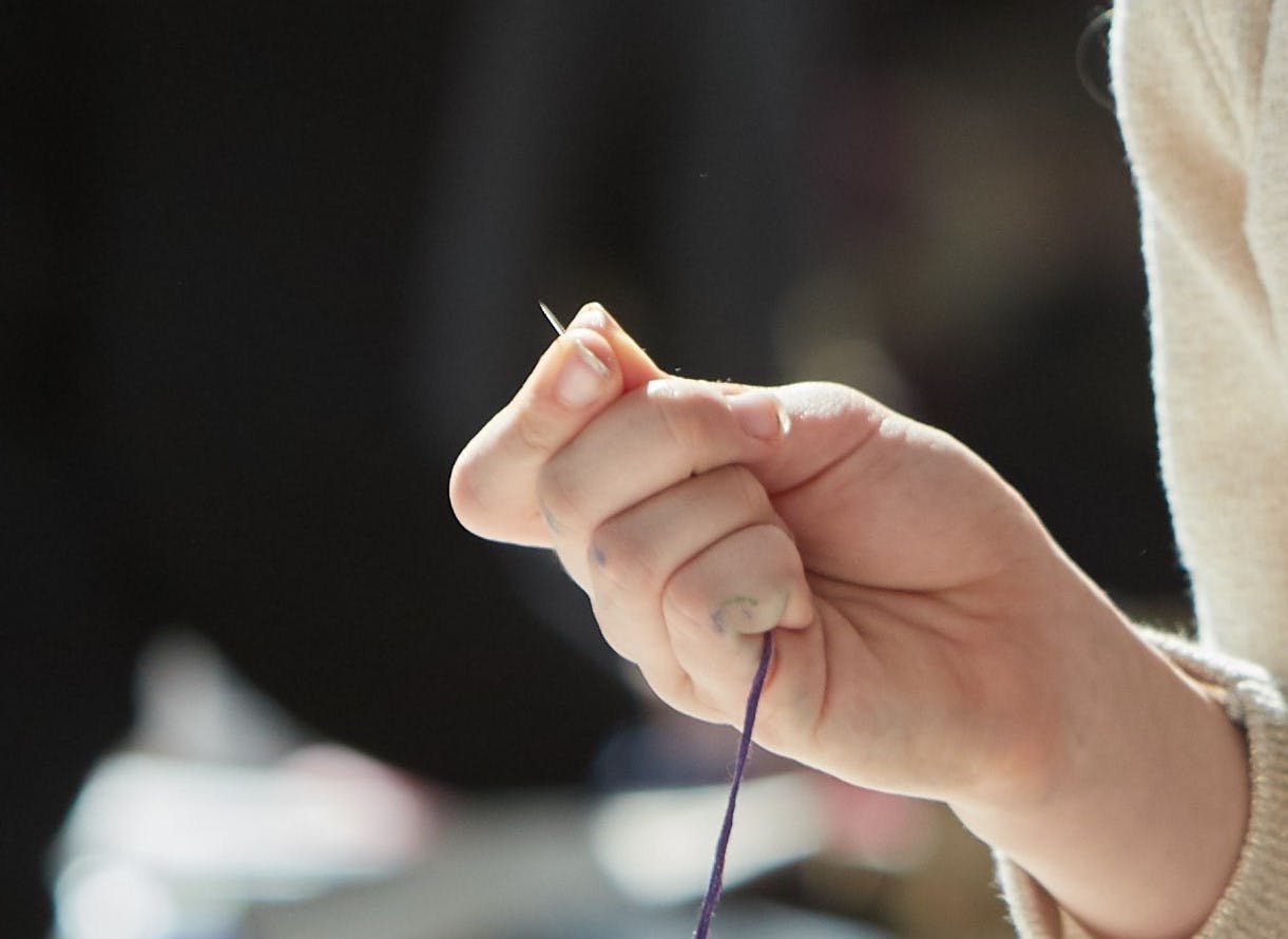 Hand holding a sewing needle and thread.