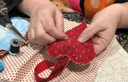 woman's hands sewing a red heart