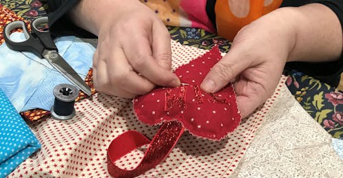 woman's hands sewing a red heart