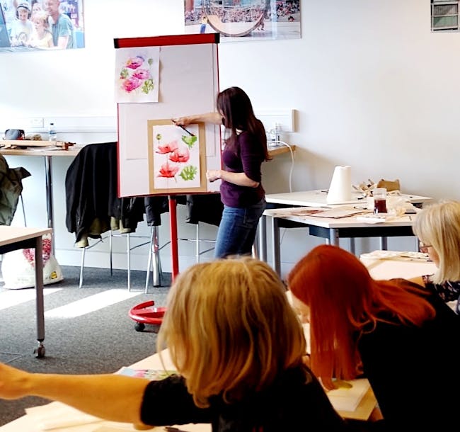 Teacher in classroom showing a watercolour painting of flowers