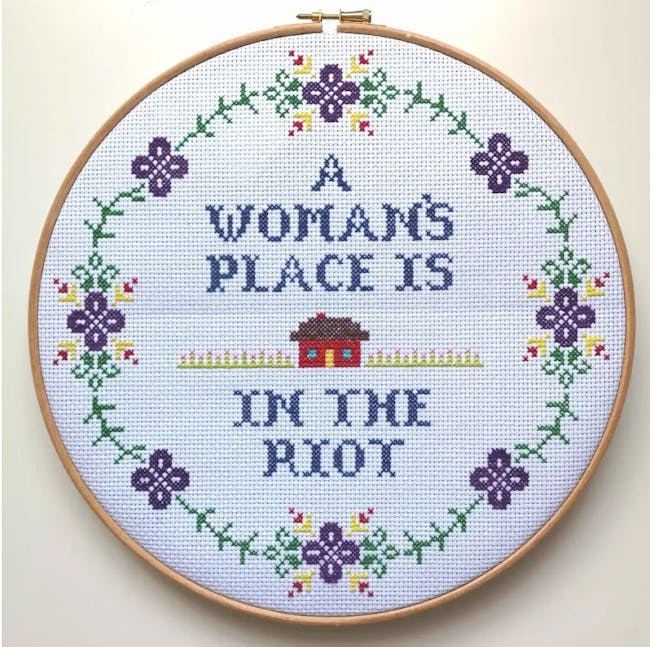Needlepoint hoop flower and text design with 'A woman's Place is in the Riot' stitched in