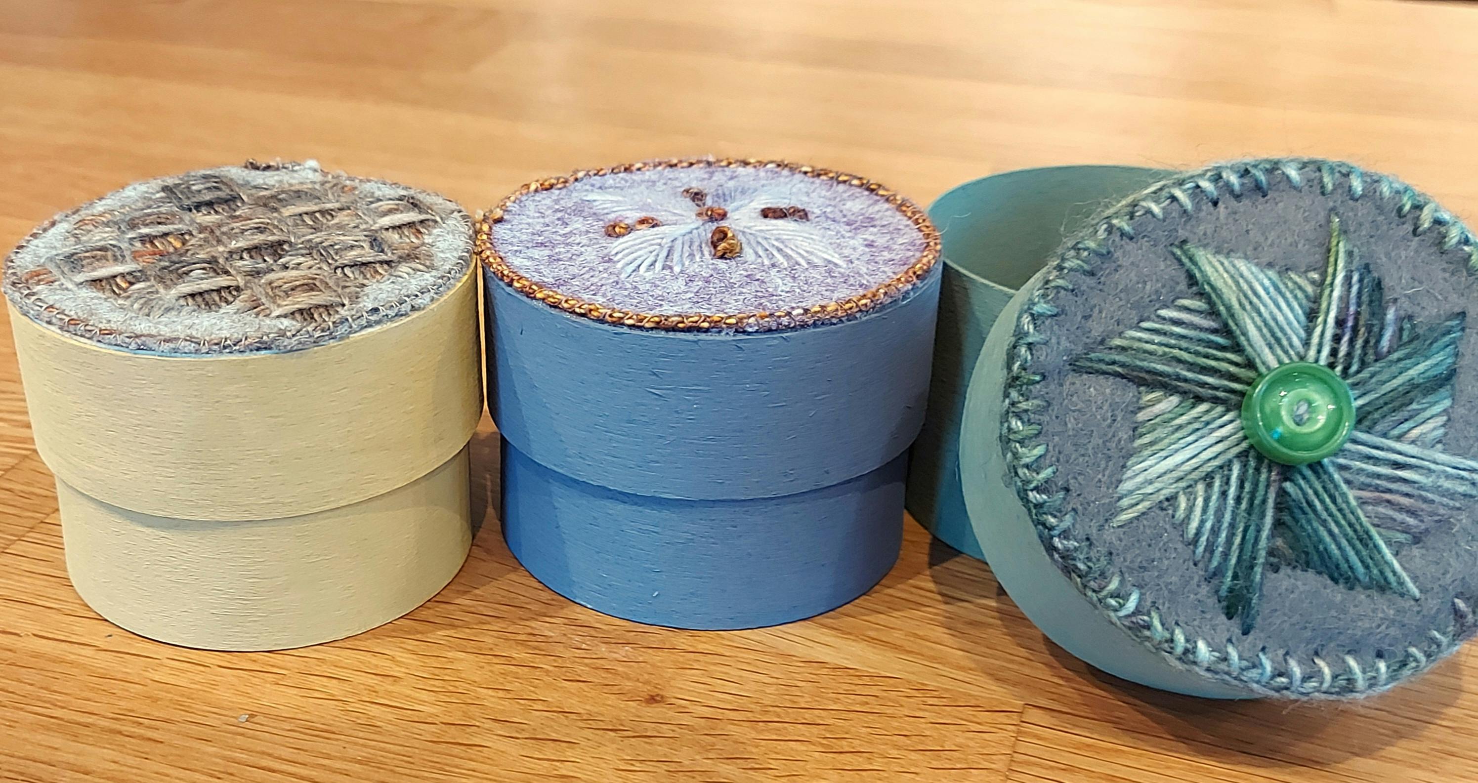 round boxes with decorative embroidered lids