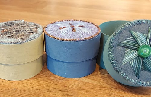 round boxes with decorative embroidered lids