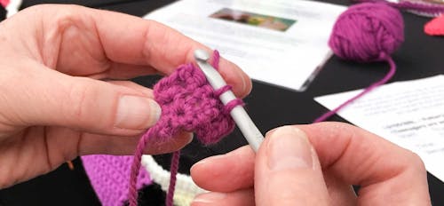female hands with crochet hooks and  pink wool