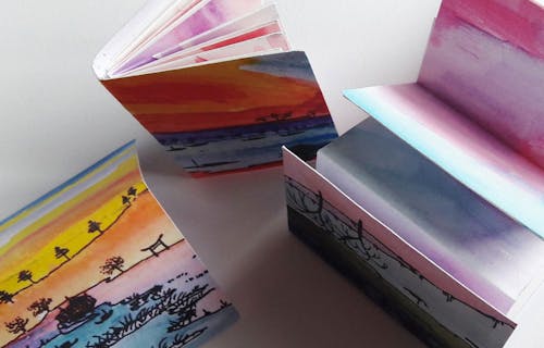 Three colourful watercolour hand made books with ink illustrations.