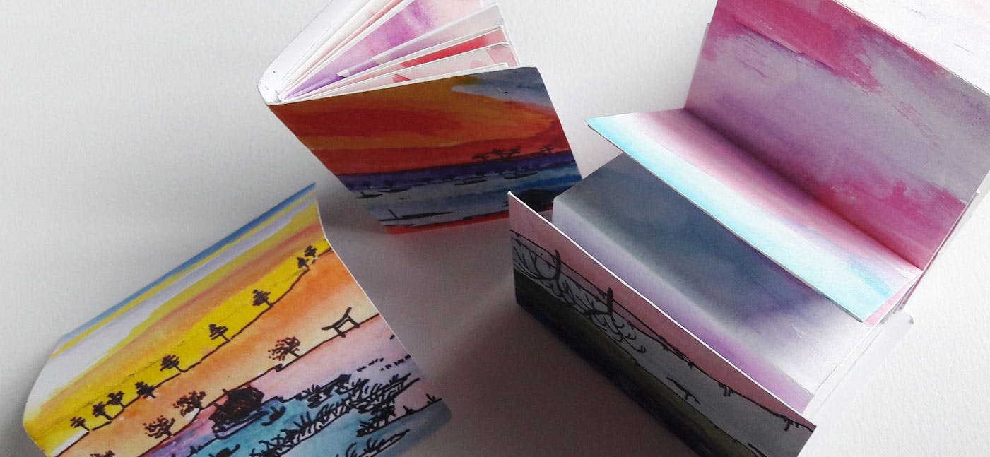 Three colourful watercolour hand made books with ink illustrations.