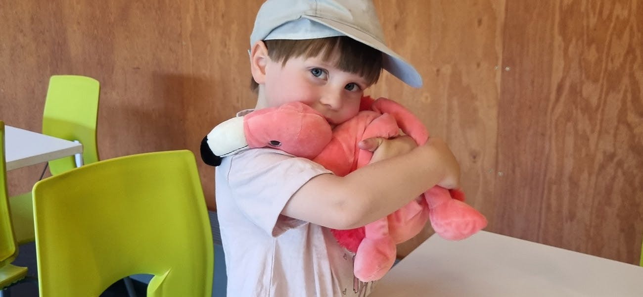 A child hugging a toy flamingo