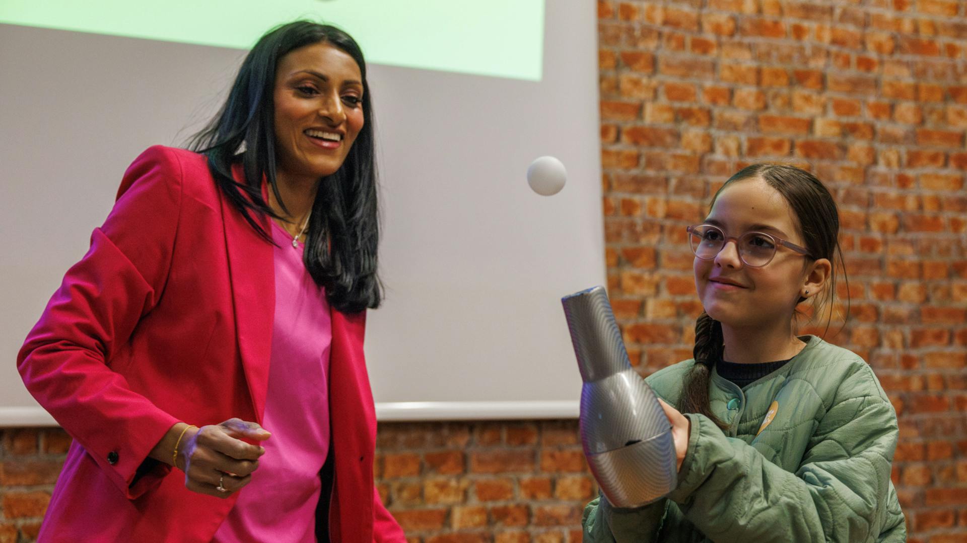 A child with Dr Shini Somara trying out a hairdryer experiment