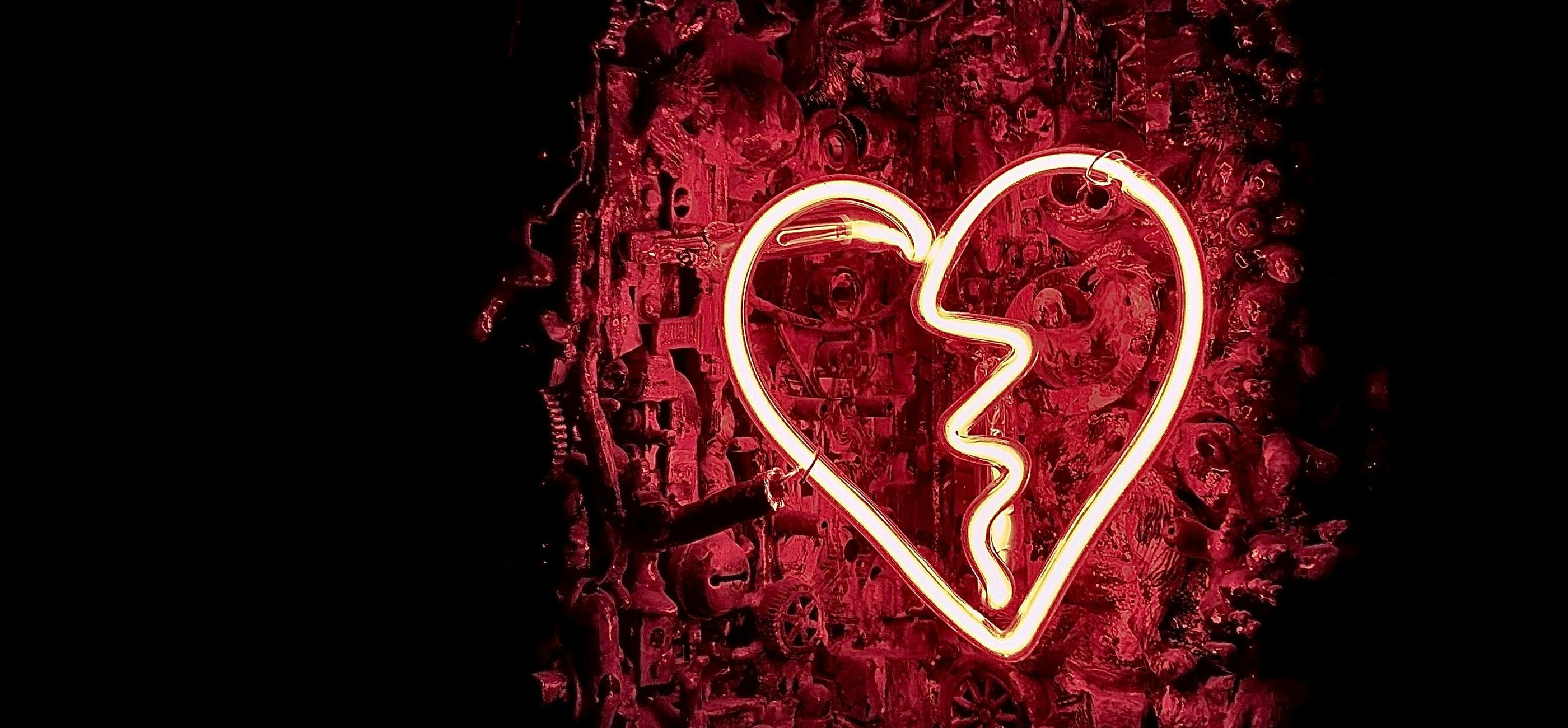 A neon heart in pink on a backdrop of red electrical items